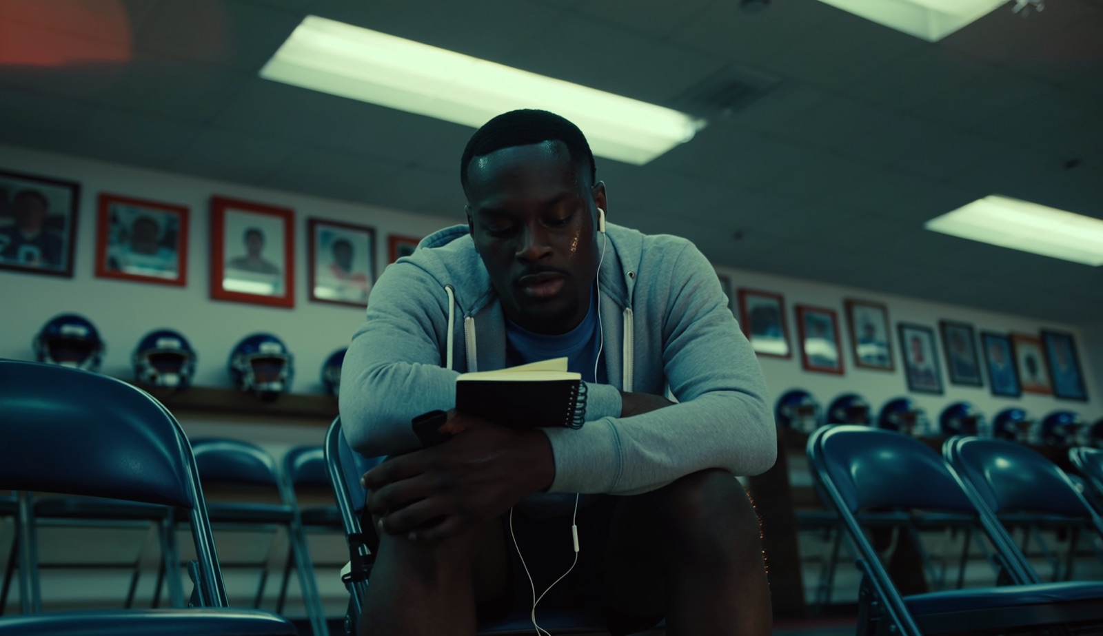 Year 3 AI-generated concept frame — a player sitting in a locker room with headphones, reading a book, moody blue cinematic lighting.